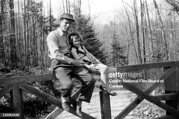 Portrait of a log driver and his daughter sitting on a fence, Quebec , Canada, 1956. Photo taken during the National Film Board of Canada's...