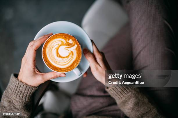 flache lay frau hand halten kaffee latte - holztisch von oben stock-fotos und bilder