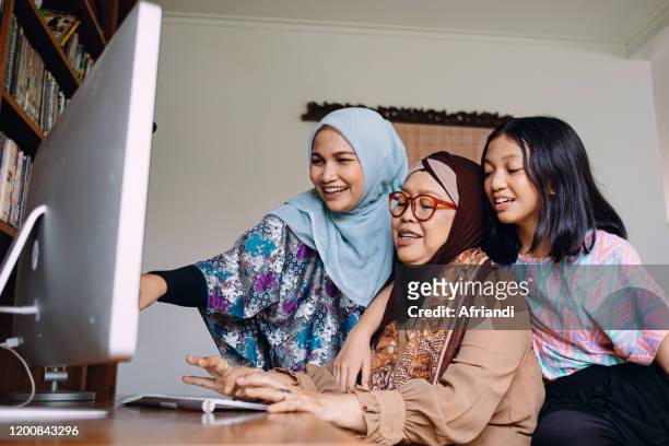 three generations in a family teaching each other with computer - malay archipelago stock pictures, royalty-free photos & images