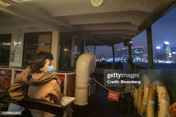 Passengers wearing protective masks travel on a Star Ferry Co. Vessel, owned by Wharf Holdings Ltd., across Victoria Harbor at night in Hong Kong,...