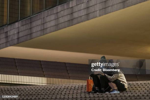 People wearing protective masks use smartphones at night in the Tsim Sha Tsui district of Hong Kong, China, on Friday, Feb. 14, 2020. As fears of the...