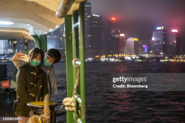 Passengers wearing protective masks pose for a selfie photograph while traveling on a Star Ferry Co. Vessel, owned by Wharf Holdings Ltd., across...