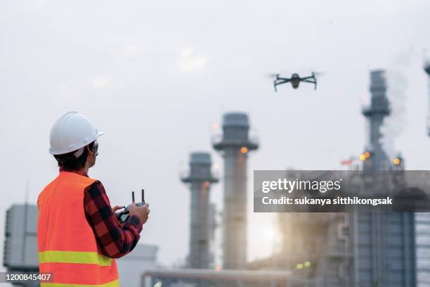 young engineer piloting drone at power plant . video surveillance or industrial inspection. - drohnen stock-fotos und bilder