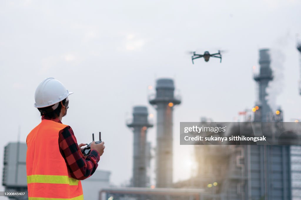 Young Engineer piloting drone at power plant . video surveillance or industrial inspection.