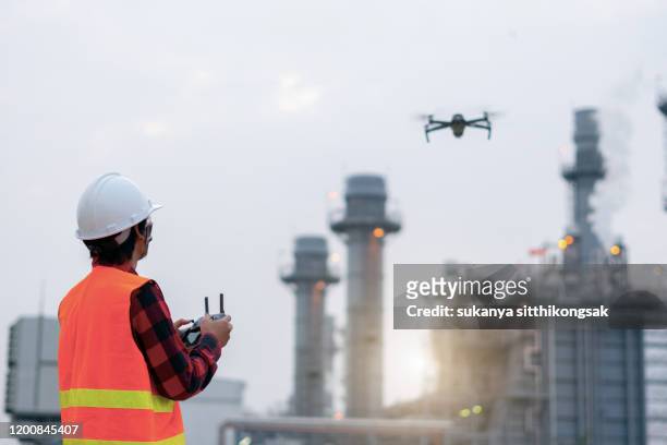 young engineer piloting drone at power plant . video surveillance or industrial inspection. - drone flying ストックフォトと画像