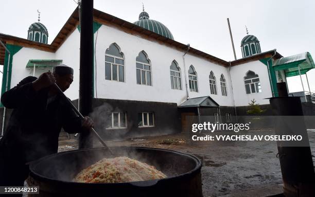 Man cooks pilau by a mosque in the majority-Dungan village of Masanchi - in southern Kazakhstan's Jambyl region close to the border with Kyrgyzstan -...