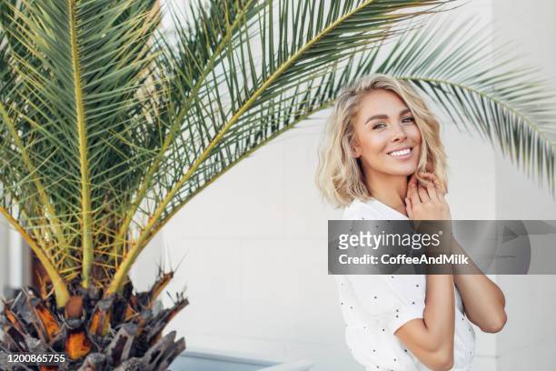 gelukkig meisje wandelen in de buurt van palmbomen op een zonnige dag in de zomer - beautiful blondes stockfoto's en -beelden