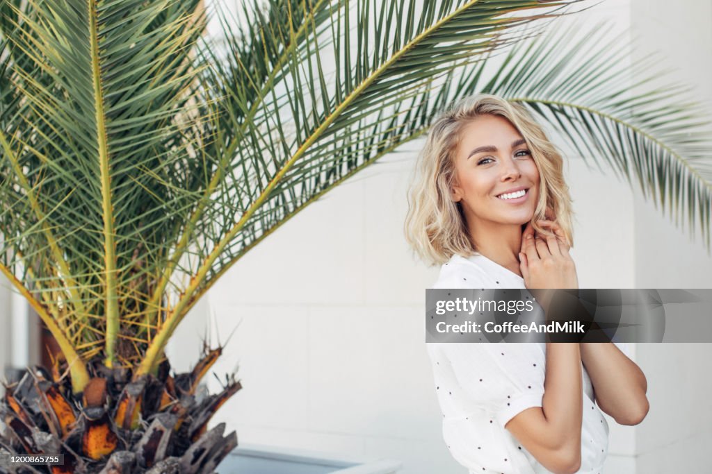 Happy girl walking near palm trees on a summer sunny day