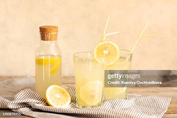 jar of tasty fresh lemonade with lemons in background - lemonade stock-fotos und bilder