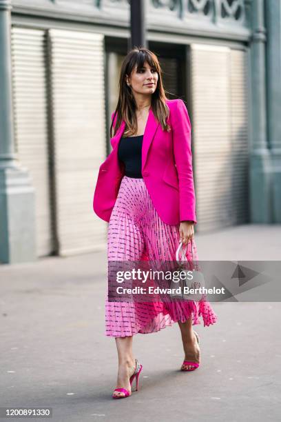 Carlotta Rubaltelli wears earrings, a necklace, a black top, a neon-pink jacket, a Miu Miu pink pleated skirt, a white Valentino bag, rhinestone...