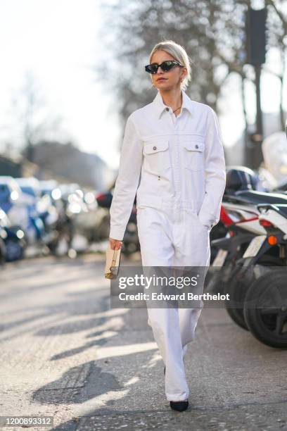 Caroline Daur wears sunglasses, a white denim jumpsuit, a Dior Saddle bag, outside Dior, during Paris Fashion Week - Haute Couture Spring/Summer...