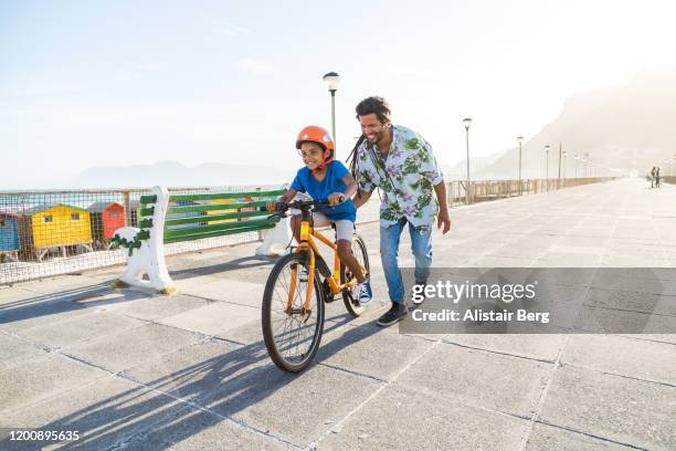 boy riding a bike with his dad - pai e filho brincando - fotografias e filmes do acervo