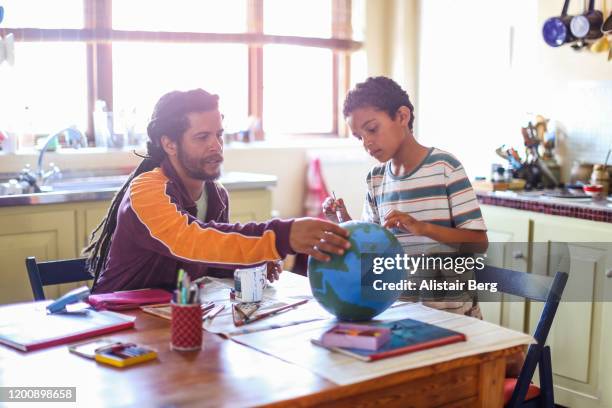 father helping his son make a globe in his kitchen - art and craft stock pictures, royalty-free photos & images