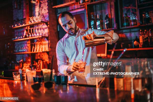 bartender pouring drinks into shot glasses from a drink shaker in a pub - bartender pouring stock pictures, royalty-free photos & images