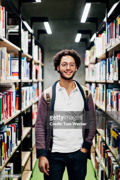 portrait of student standing in library aisle - choice student stockfoto's en -beelden