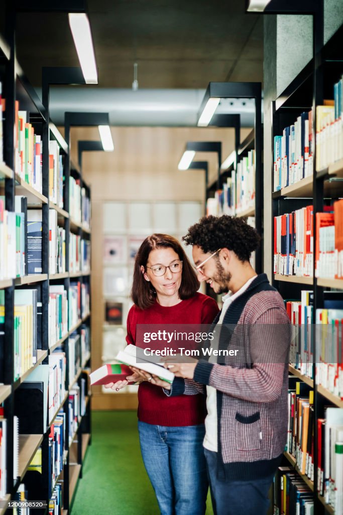 Talking In The Library Two People Talking While Selecting Books In Public Library High-Res ...