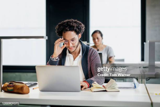 young man studying on laptop in library - higher education stock-fotos und bilder