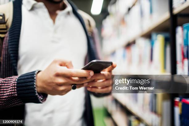 close up of man using smartphone in libarary - midsection stock pictures, royalty-free photos & images