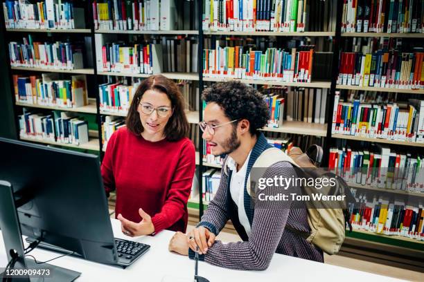 librarian helping student locate books for his studies - librarian stock pictures, royalty-free photos & images