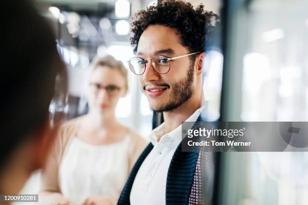close up of young man talking to colleague in public library - male student wearing glasses with friends stockfoto's en -beelden