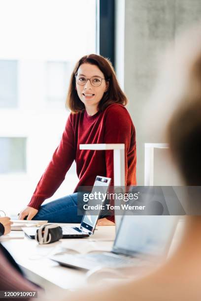 teacher leaning on desk while talking to students. - school teacher blue stock-fotos und bilder