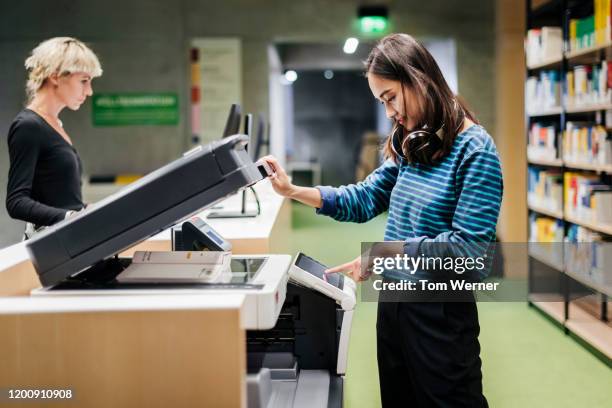 student using photocopier in library - kopiergerät stock-fotos und bilder