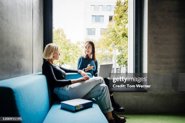 two friends chatting in quiet library space - campus ストックフォトと画像