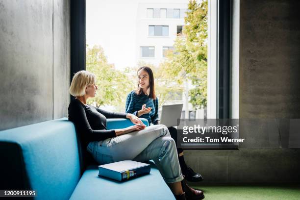 two friends chatting in quiet library space - legs crossed at knee stock pictures, royalty-free photos & images