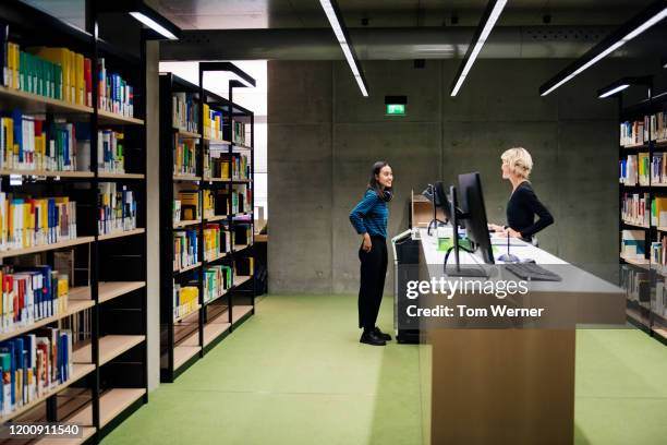 student talking to librarian in modern library - librarian ストックフォトと画像