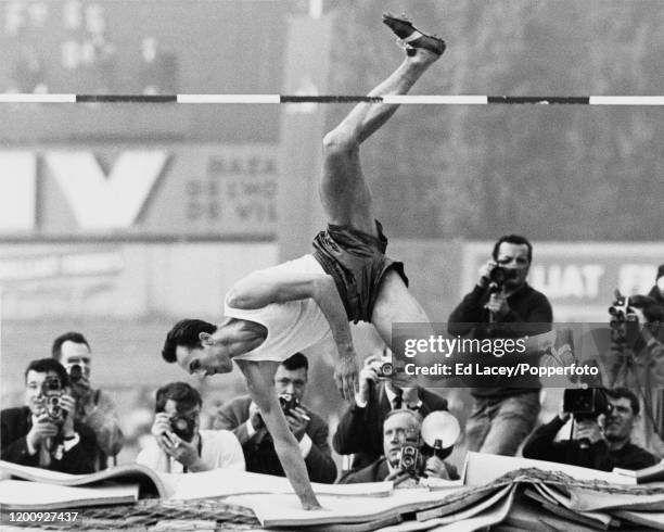 Russian high jumper Valeriy Brumel competes for the Soviet Union in a high jump competition in front of a group of sports press photographers at an...