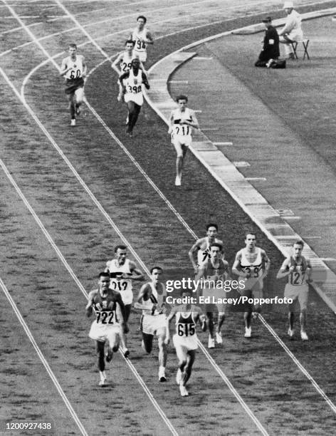 Billy Mills of the United States team passes Ron Clarke of Australia and prepares to overtake Mohammed Gammoudi of Tunisia to finish in first place...