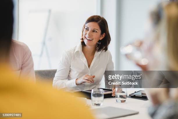 vrolijke medio volwassen vrouw die bij bedrijfsvergadering glimlacht - professional occupation stockfoto's en -beelden