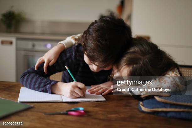 a 9 year old boy doing his homework with his sister - enfant cartable photos et images de collection