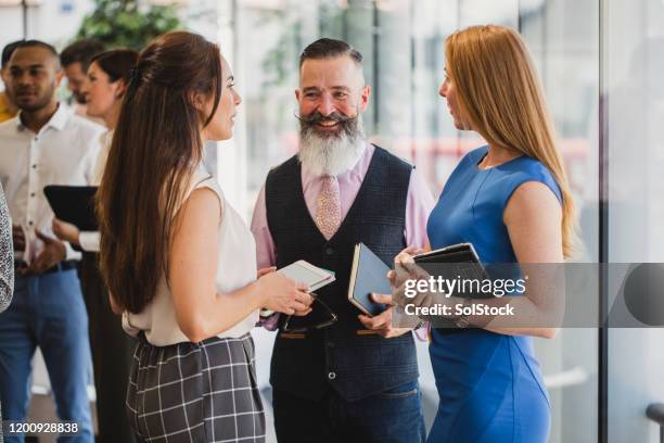 hombre de negocios hipster con barba hablando con colegas femeninas - bigote manillar fotografías e imágenes de stock