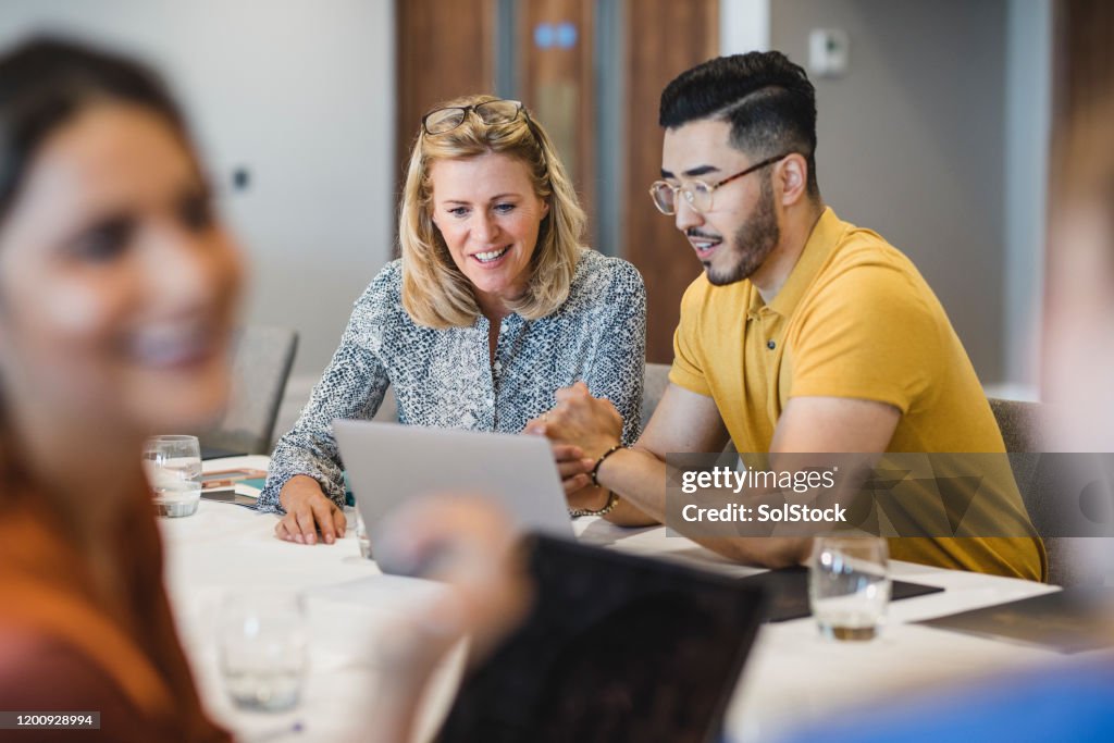 Hipster young man showing female colleague laptop