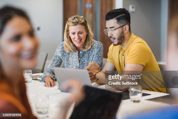 hipster young man showing female colleague laptop - gerente imagens e fotografias de stock