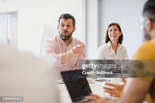 Businessman with beard explaining in meeting with colleagues Businessman with beard explaining in meeting with colleagues