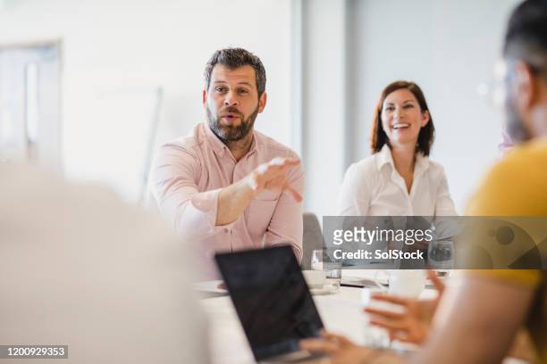 businessman with beard explaining in meeting with colleagues - paparazzi stock pictures, royalty-free photos & images