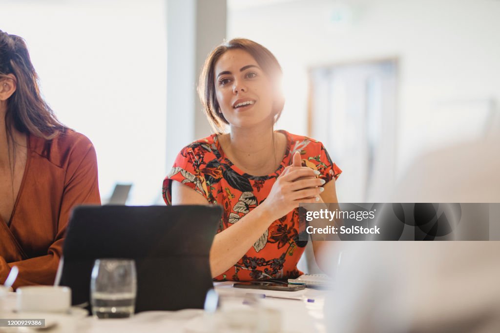 Jeune femme d'affaires confiante écoutant soigneusement à la table de conférence