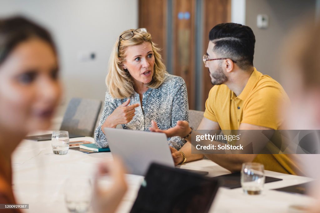 Mature businesswoman discussing with colleague using laptop