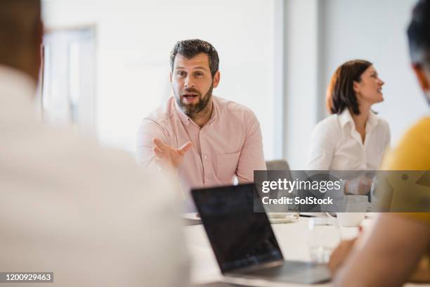 mature man with beard talking to colleagues at conference table - managing director office stock pictures, royalty-free photos & images