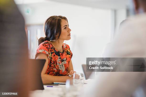 attraktive junge frau sitzt am tisch in business-meeting - listening stock-fotos und bilder