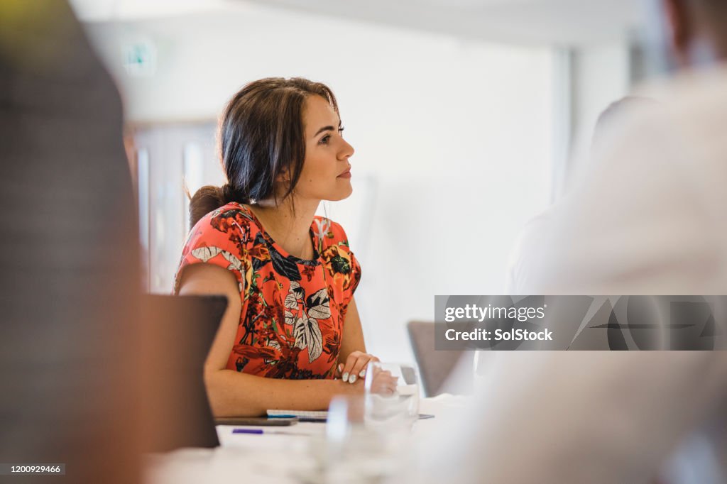 Attractive young woman sitting at table in business meeting