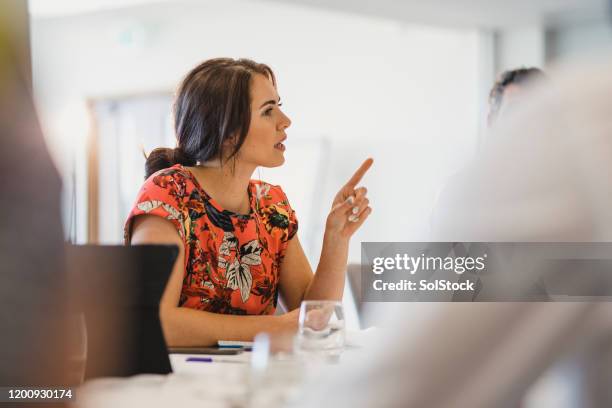 selbstbewusste junge geschäftsfrau erklärt in arbeitstreffen - business woman pointing stock-fotos und bilder