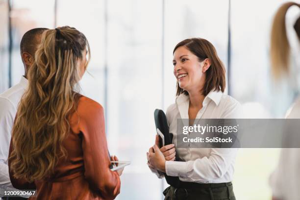 businesswoman smiling with young colleagues at work event - business women networking stock pictures, royalty-free photos & images