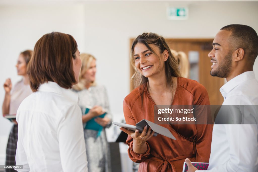 Giovani colleghi allegri che discutono con il tablet digitale