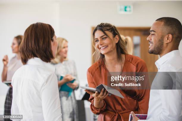 cheerful young colleagues discussing with digital tablet - connection stock pictures, royalty-free photos & images