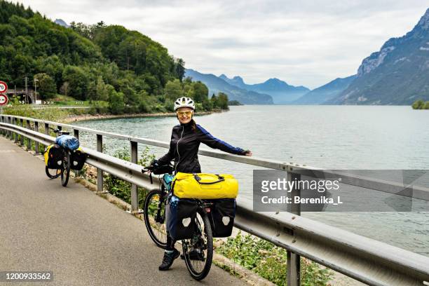 glücklicher radfahrer posiert auf dem hintergrund von bergen und see. - fahrradausflug stock-fotos und bilder
