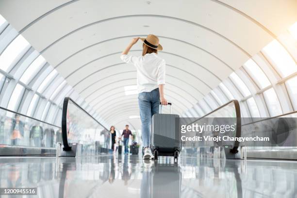 young woman wearing casual clothes and walking in the airport hall - maleta fotografías e imágenes de stock