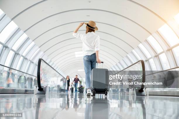 young woman wearing casual clothes and walking in the airport hall - スーツケース ストックフォトと画像